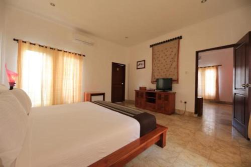 a bedroom with a large bed and a television at Aaliku Bungalows in Gili Trawangan