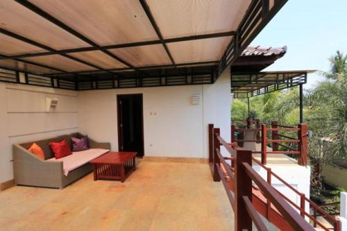 a covered patio with a couch and a table at Aaliku Bungalows in Gili Trawangan