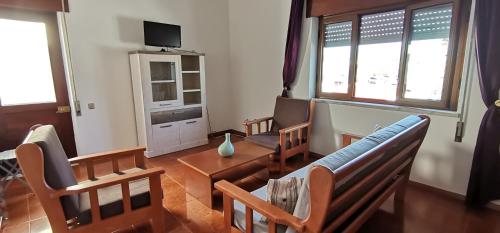 uma sala de estar com cadeiras, um sofá e uma mesa em Apartamentos Guiomar Campos em Porto Covo