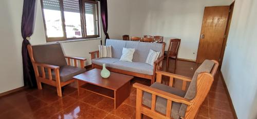 a living room with a couch and chairs and a table at Apartamentos Guiomar Campos in Porto Covo