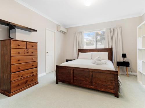 a bedroom with a bed and a dresser and a window at Aqua La Vista Mandurah in Mandurah