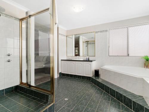a bathroom with a large tub and a shower at Aqua La Vista Mandurah in Mandurah