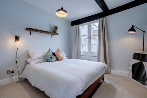 a bedroom with a white bed and a window at Stunning designer apartment in an ancient building in Norwich