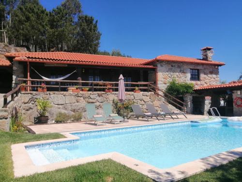a swimming pool with chairs and a house at Casa da Montanha in Rebordões