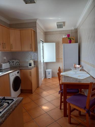 kuchnia ze stołem i białą lodówką w obiekcie T2,Casa Sol e Mar 50464/AL w mieście Vila Nova de Milfontes