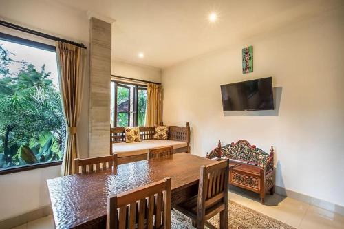 ein Esszimmer mit einem Tisch und einem Sofa in der Unterkunft The Radian Villa Ubud in Ubud