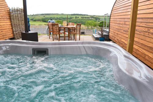 a hot tub in a backyard with a table and chairs at Derecroft Glamping Luxury Lodgepods in Lanchester