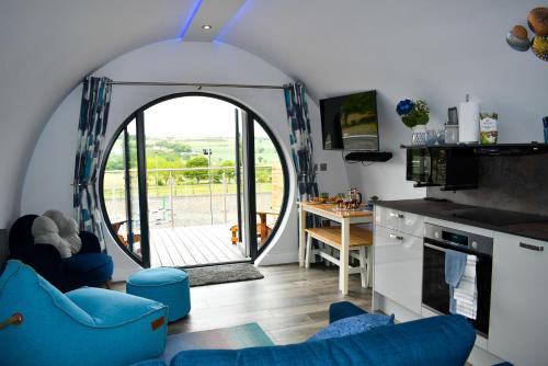 a living room with an arched doorway and a kitchen with blue chairs at Derecroft Glamping Luxury Lodgepods in Lanchester