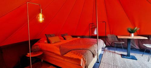 1 dormitorio rojo con 1 cama en una tienda de campaña en Fiertelmeers Boutique Glamping, en Ronse