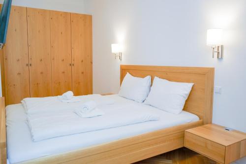 a bed with white sheets and a wooden headboard at Nadland Apartments B7 in Vienna