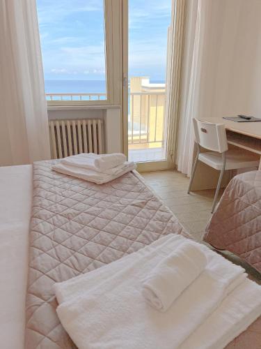 a bedroom with two beds and a view of the ocean at Hotel Ambassador in Laigueglia