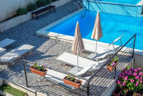 twee stoelen en parasols naast een zwembad bij Apartments Golden View in Kotor