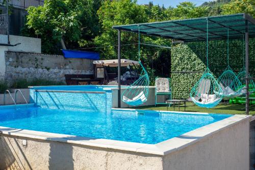 a large swimming pool with a canopy and swings at Apartments Golden View in Kotor