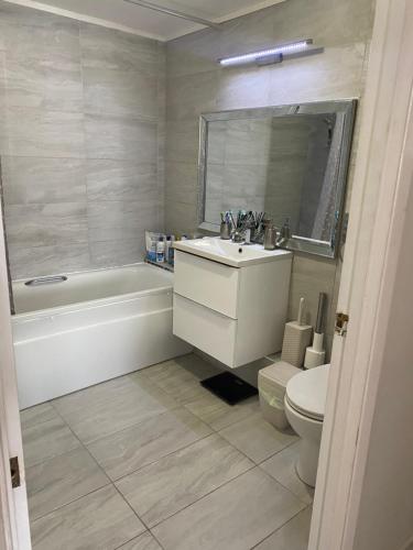 ein Badezimmer mit einem Waschbecken, einer Badewanne und einem WC in der Unterkunft Modern 2 bedrooms fully equipped Apartment with garden, Free Parking, Free Wifi in Dagenham