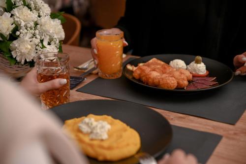 a table topped with plates of food and orange juice at Hotel Vertigos in Tuzla