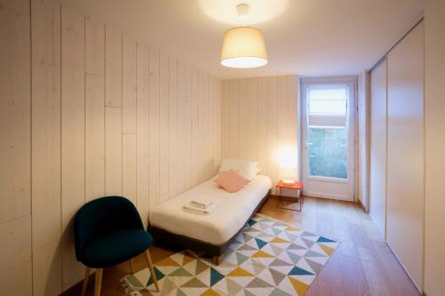 um quarto com uma cama, uma cadeira e uma janela em Appartement sur les quais de Bordeaux em Bordeaux