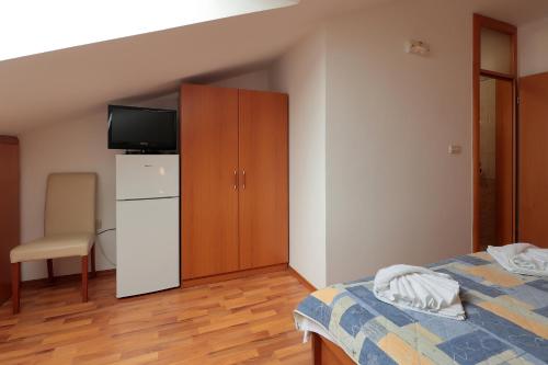 a bedroom with a bed and a cabinet with a television at Resort Trcol in Novalja