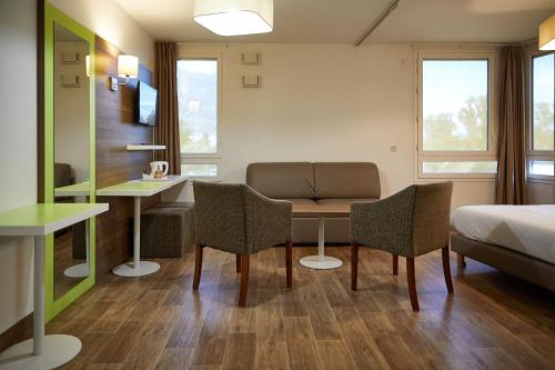 a hotel room with a bed and a table and chairs at The Originals Résidence, Grenoble Université in Saint-Martin-dʼHères