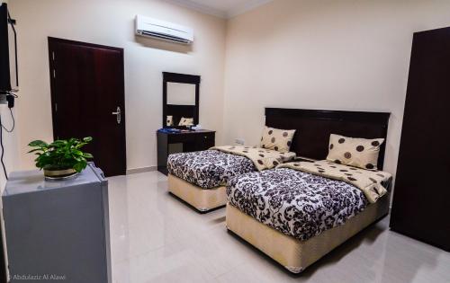 a bedroom with two beds and a television in it at Al Jumhour Hotel Apartments in Sur