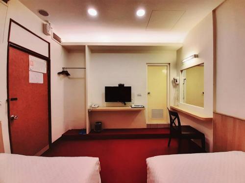 a room with two beds and a desk with a television at Long Cherng Hotel in Luodong