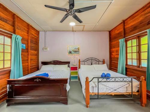 a bedroom with two beds and a ceiling fan at Betik Garden Home in Machang
