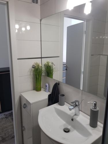 a white bathroom with a sink and a mirror at Alex Apartman in Békéscsaba
