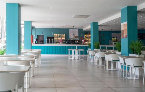 a restaurant with white tables and white chairs at Hotel Roquetas El Palmeral by Pierre & Vacances in Roquetas de Mar