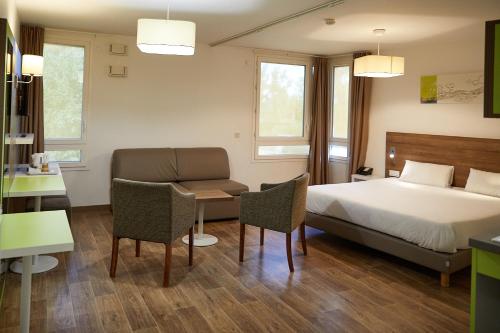 a bedroom with a bed and a table and chairs at The Originals Résidence, Grenoble Université in Saint-Martin-dʼHères