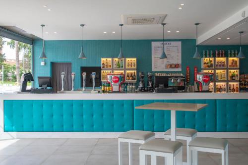 a bar in a restaurant with a blue wall at Hotel Roquetas El Palmeral by Pierre & Vacances in Roquetas de Mar