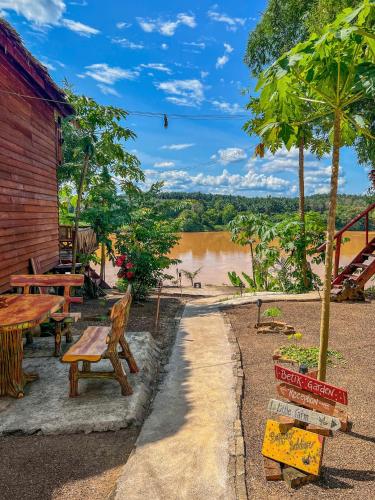 a picnic table and benches next to a river at Betik Garden Home in Machang