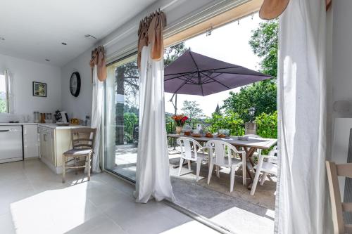 - une cuisine et une salle à manger avec une table et un parasol dans l'établissement Villa Clémentine, à Gravières