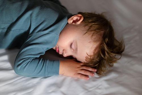 a young child is sleeping on a bed at Strandhotel Kurhaus Juist in Juist