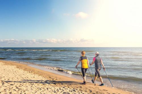 two people walking on the beach with paddles at Strandhotel Kurhaus Juist in Juist