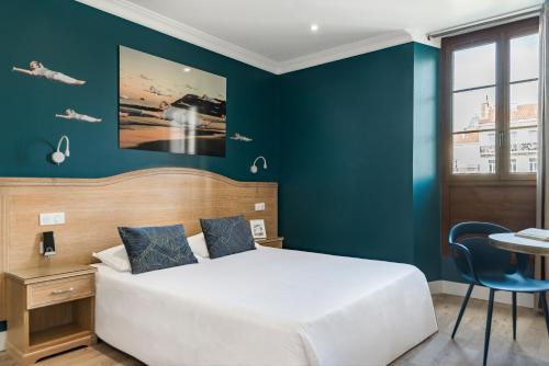 a bedroom with a bed and a blue wall at The Originals Boutique, Grand Hôtel de la Gare, Toulon in Toulon