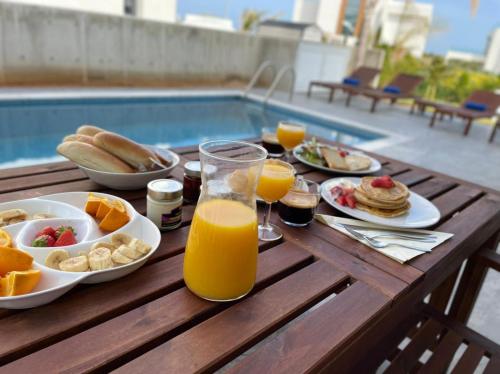 a wooden table with breakfast foods and orange juice at By the Beach Villa Natalya in Protaras