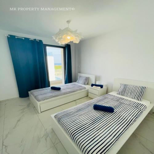two beds in a room with a window at By the Beach Villa Natalya in Protaras