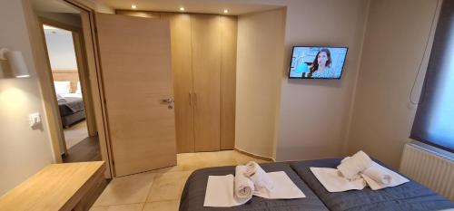 a hotel room with a bed with towels and a tv at Villy Luxury Home 1 in Ayiá