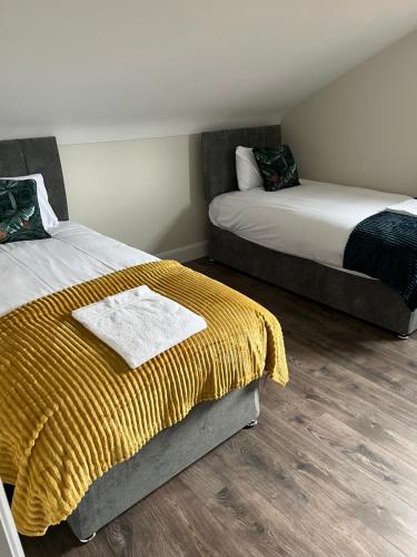 a bedroom with two beds with yellow blanket and wood floors at Oakwell holiday village in Ramelton