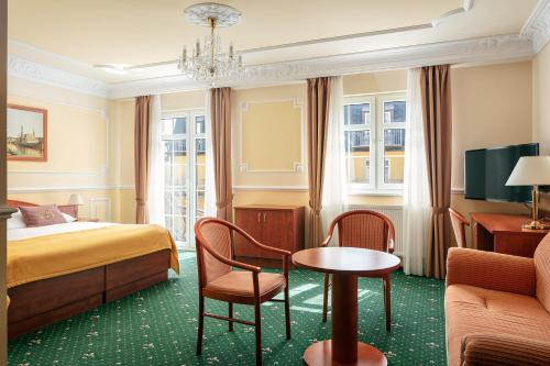 ein Hotelzimmer mit einem Bett, einem Tisch und Stühlen in der Unterkunft Hotel Bajkal in Franzensbad