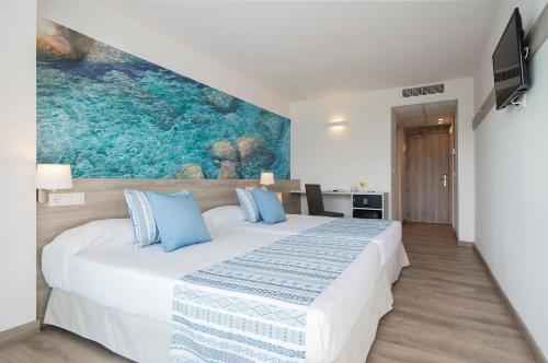 a bedroom with a large white bed with blue pillows at Hotel Roquetas El Palmeral by Pierre & Vacances in Roquetas de Mar