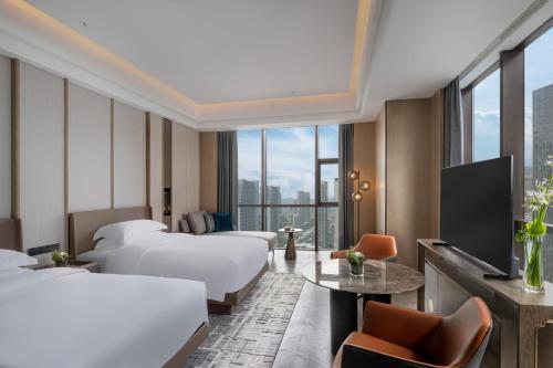 杭州市にあるInterContinental Hangzhou Liangzhu, an IHG Hotelのベッド2台とテレビが備わるホテルルームです。