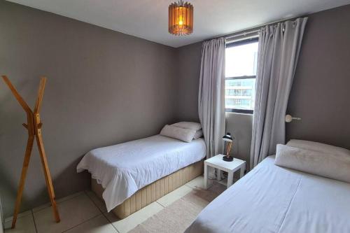 a small bedroom with two beds and a window at Elpizo Vista in East London
