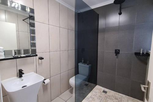 a bathroom with a sink and a toilet and a shower at Elpizo Vista in East London