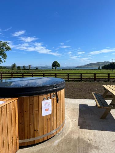 a hot tub sitting next to a picnic table and a bench at Oakwell holiday village in Ramelton