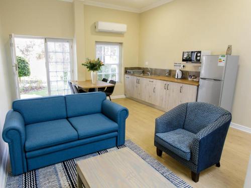 a living room with a blue couch and a chair at Queens Hotel by BON Hotels in Oudtshoorn