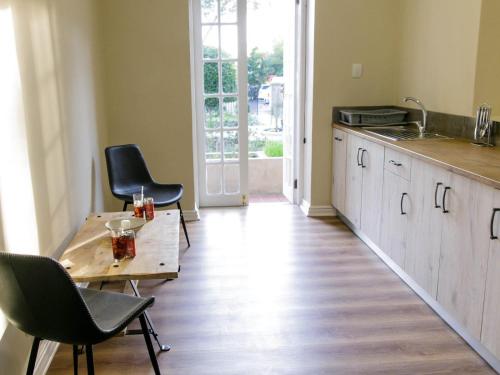 eine Küche mit einem Tisch und Stühlen sowie Holzböden in der Unterkunft Queens Hotel by BON Hotels in Oudtshoorn