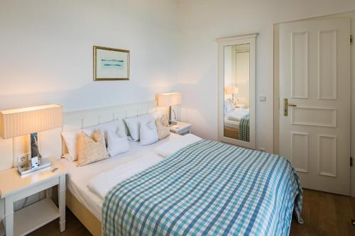 a white bedroom with a bed and a desk and a mirror at Strandhotel Kurhaus Juist in Juist