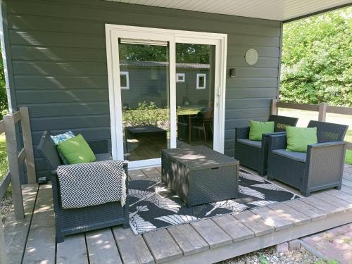 een patio met stoelen en een tafel op een huis bij 4p chalet TOLVE met 4 fietsen vlakbij natuurgebieden Drents Friese Wold, Fochteloërveen en gevangenisdorp Veenhuizen in Oosterwolde