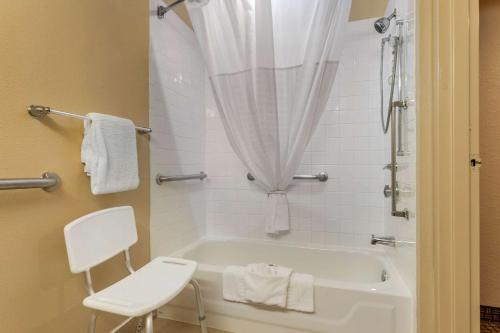 a white bathroom with a tub and a chair at Sonesta Essential NW Houston in Houston