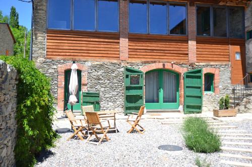 un patio con sillas y una casa con puertas verdes en Apartament Cal Josepó, en Ger